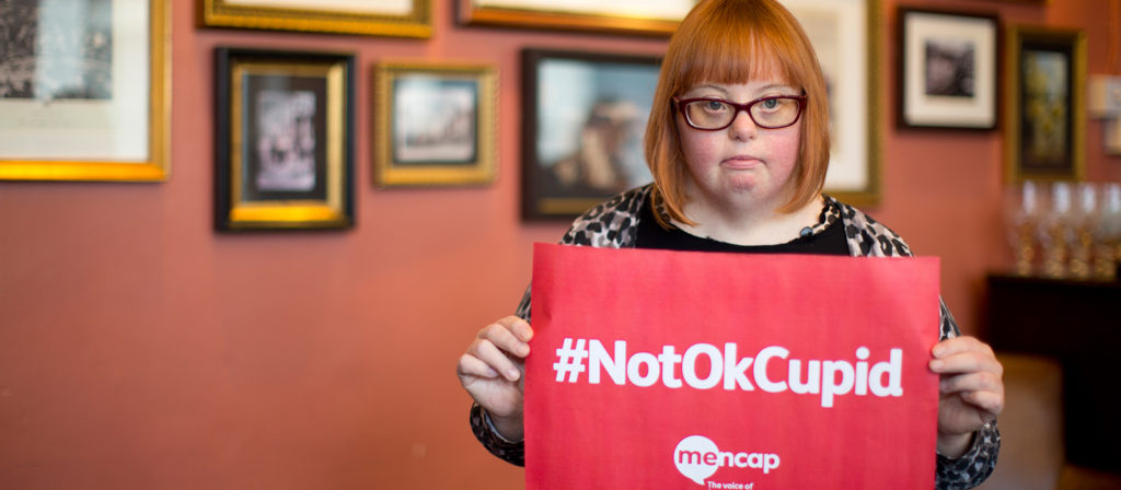 Kate Brackley from mencap holding a sign with #NotOkCupid written on it